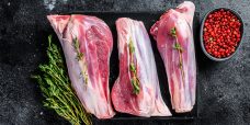 Raw goat shanks meat on a marble board. Black background. Top vi