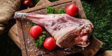 lamb leg on the wooden board prepared for cook tomato broccoli salt top view