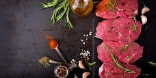 Raw beef steaks with spices and rosemary. Flat lay.Top view