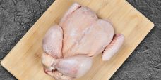 Raw whole chicken on wooden chopping board