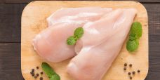 Set raw chicken on cutting board on the wooden background