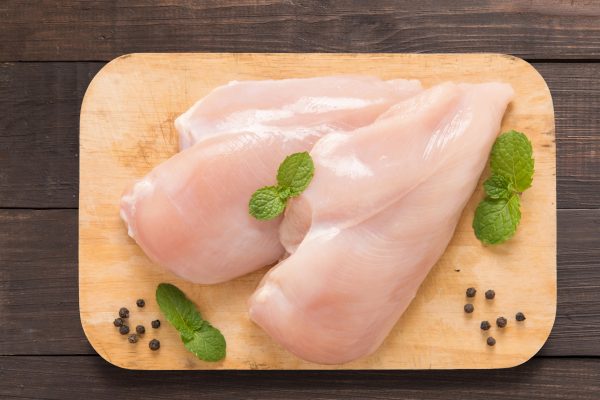 Set raw chicken on cutting board on the wooden background